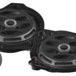 Pair of round black car speakers with mounting frames and upgrade badges (left and right units).