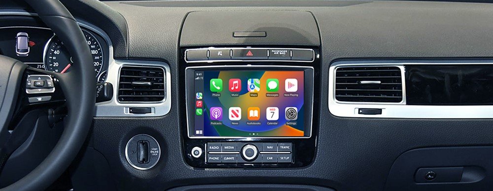 Car interior showing a center touchscreen displaying Apple CarPlay, flanked by A/C vents and dashboard controls.